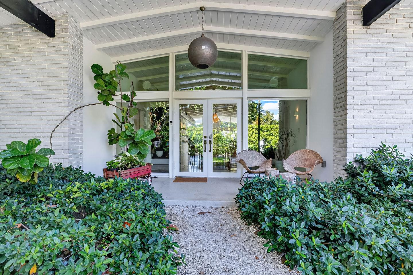 Front entrance covered porch with lush tropical landscaping