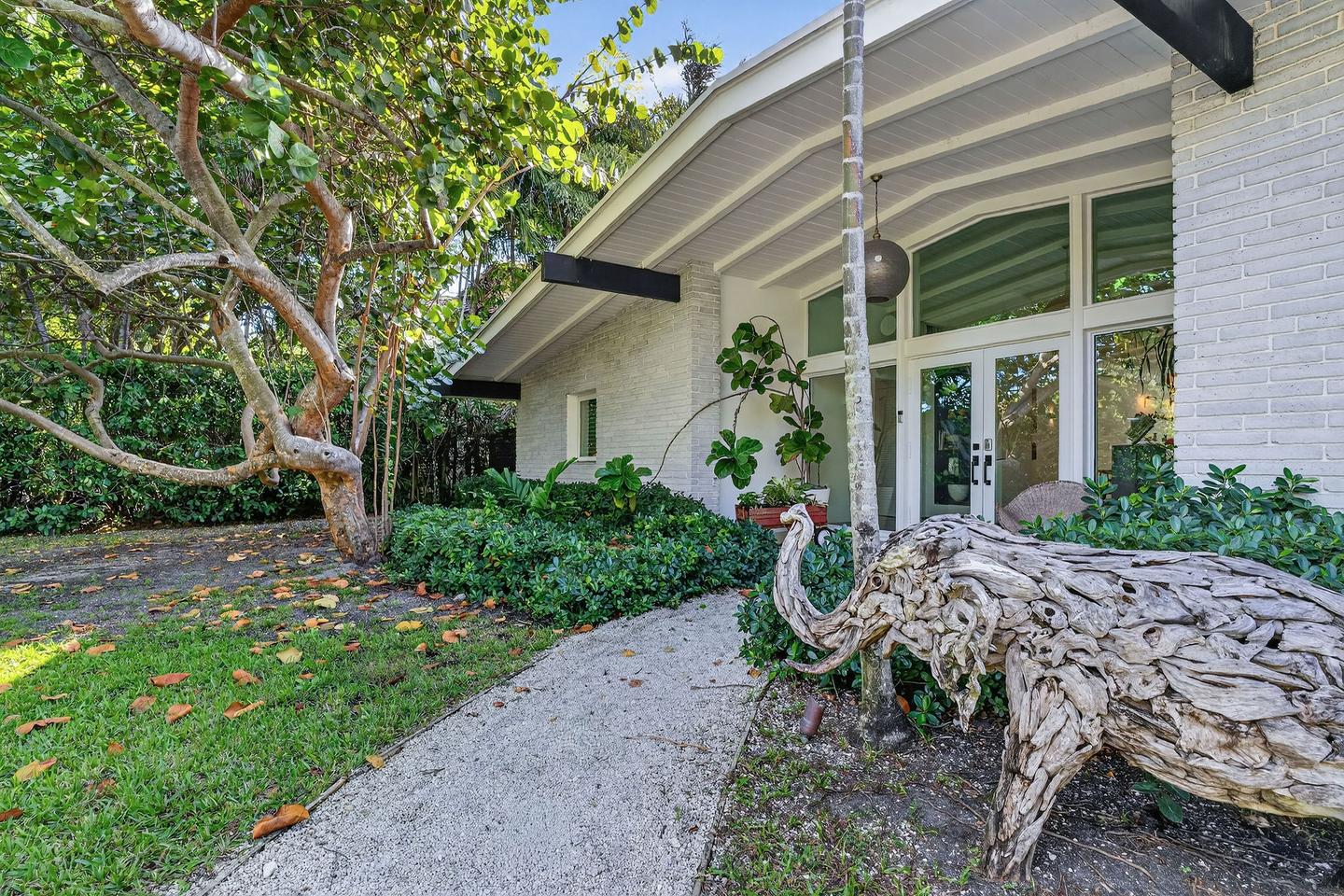 Side elevation with mature landscaping and driftwood sculpture