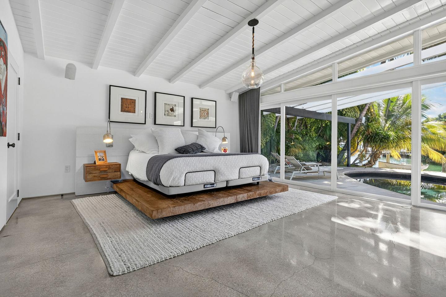 Primary bedroom with vaulted ceiling and pool view
