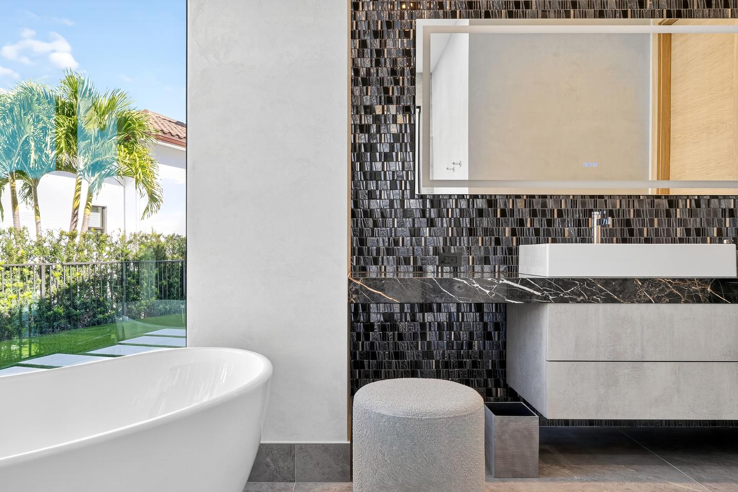 Primary bath — freestanding tub with garden view and dark mosaic tile vanity