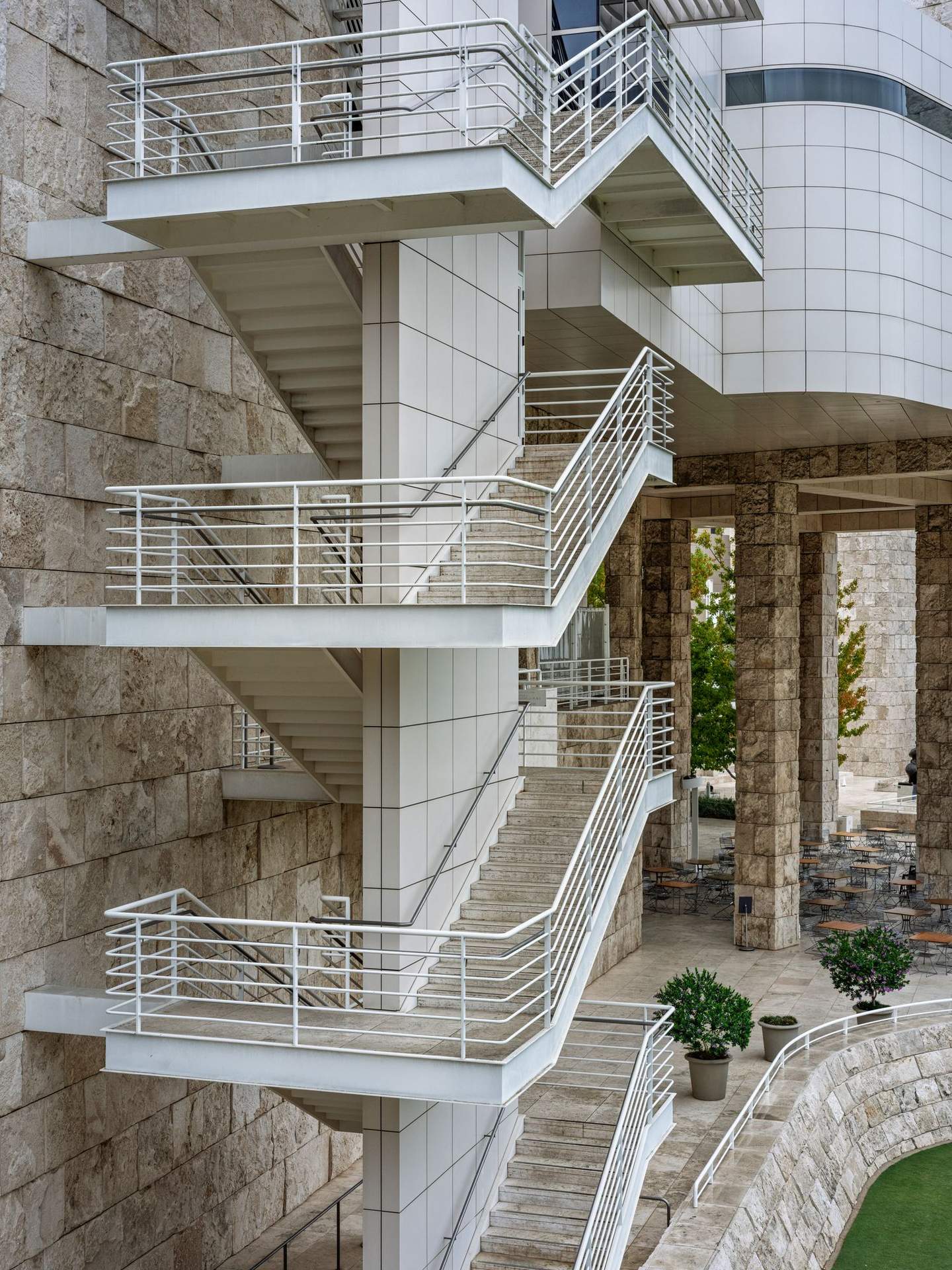 Getty Center staircase railing and landing detail, travertine cladding grid and open-air construction visible with planted terrace level behind