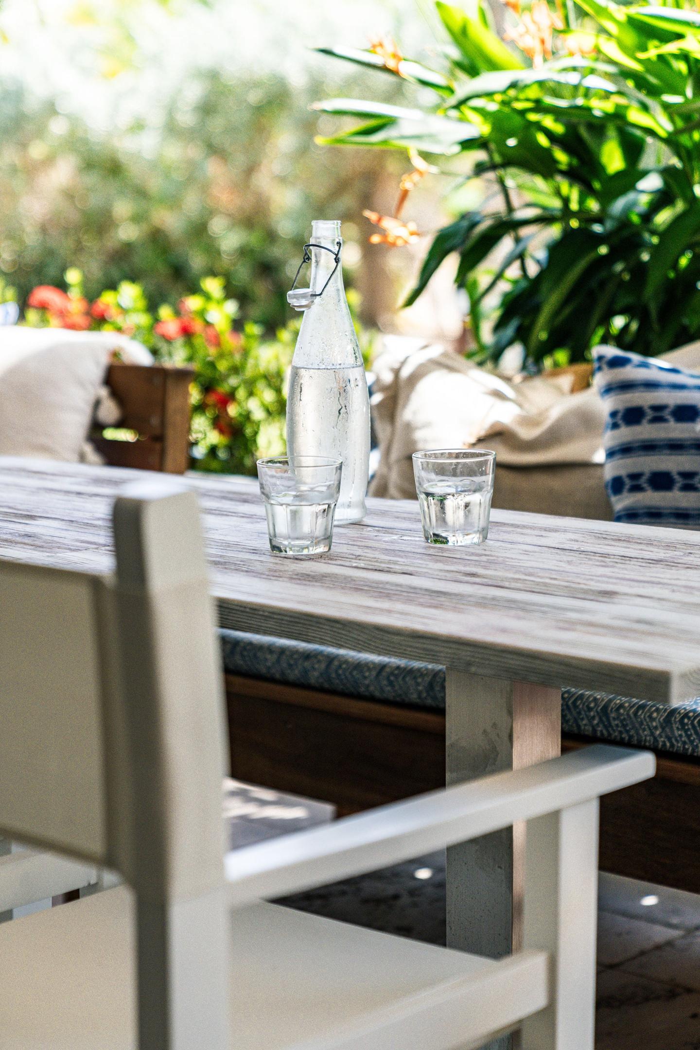 Garden dining detail with carafe and stoneware glasses
