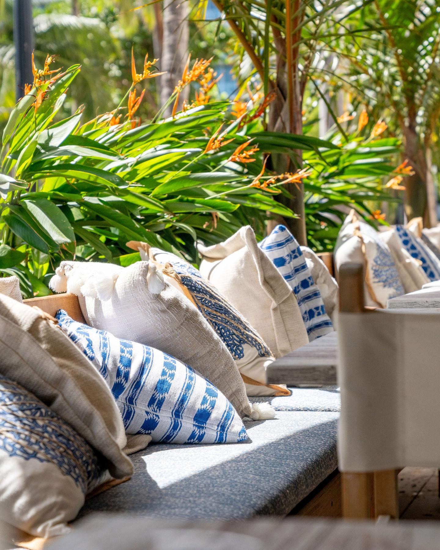 Tropical lounge seating with patterned pillows and heliconia bloom