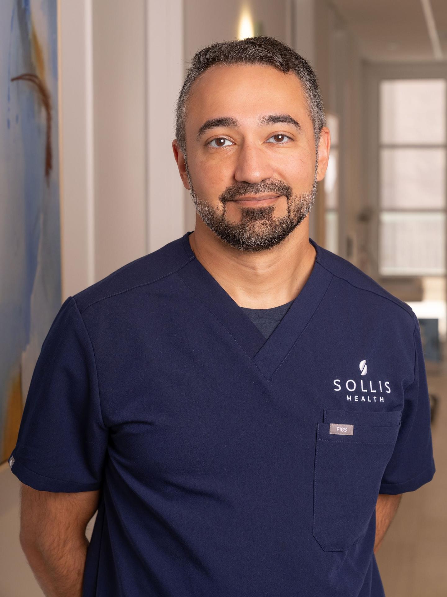 Male clinician portrait in branded Sollis Health scrubs